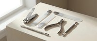 Professional manicure pedicure tools set on white surface including nail clippers, cuticle nippers, tweezers and files for salon beauty care.