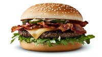 Juicy cheeseburger with crispy bacon strips, melted cheese, fresh lettuce and pickles on sesame seed bun against white background, ready for menu or advertising.