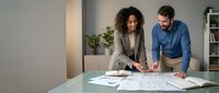 Young diverse business professionals collaborating on architectural plans in modern office workspace for project development and teamwork.
