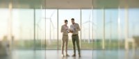 Business professionals discussing project in modern office with glass walls and city view background for corporate presentations.