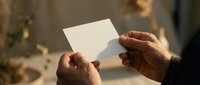 Hands holding blank white card with soft natural lighting and blurred background for mockup design projects and branding presentations.