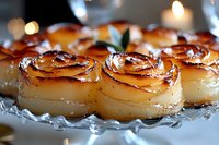 Golden potato roses baked in foil with herbs, elegant side dish for holiday dinner or gourmet cooking presentation with warm bokeh lights background.