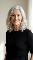 Confident senior woman with silver gray hair smiling warmly in black sweater, representing mature beauty and positive aging lifestyle.