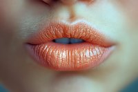 Close-up of woman's lips with glossy coral lipstick showing natural texture and shine for beauty and cosmetics applications.