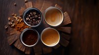 Four small bowls on wooden board showing coffee in different forms: whole beans, ground coffee, and fresh brewed espresso with crema, viewed from above on dark surface.