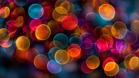 Vibrant colorful bokeh lights background with overlapping circles in rainbow hues creating magical atmosphere for festive celebrations and holiday designs.