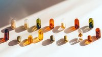 Colorful transparent medicine capsules and pills casting long shadows on white surface in minimalist composition, pharmaceutical concept for healthcare.