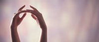 Two hands forming a heart shape against a soft, blurred background with warm golden light, symbolizing love, care, compassion, and human connection for healthcare and wellness concepts.