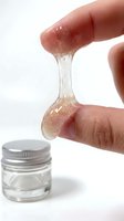 Closeup of hand stretching translucent gel with glitter particles, demonstrating skincare product texture and consistency for cosmetic, beauty, and personal care applications.