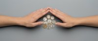 Hands protecting pile of coins arranged in circle on gray surface, symbolizing financial security, savings, and wealth management.