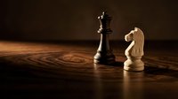 Chess pieces on wooden board with dramatic lighting showcasing strategic game concept for business and competition themes.