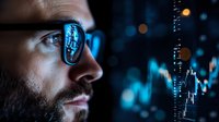 Close up profile of bearded man looking at financial trading charts and market data reflected in glasses with blue glow from digital screen in dark room.