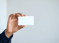 Male hand holding blank white business card against neutral background, suitable for branding, corporate identity, and marketing presentations.