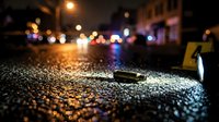Car keys dropped on wet asphalt street at night with blurred city lights and traffic in background creating bokeh effect for safety and responsibility concepts.