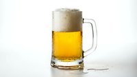 Frothy golden beer in glass mug with handle on white background, suitable for beverage advertising, restaurant menus, and pub promotions.