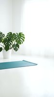 Minimalist yoga studio setup with rolled teal mat, potted monstera plant, and bright white interior space for wellness and fitness design projects.