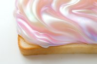 Slice of toast topped with swirled iridescent pastel cream in pink, white and lavender tones, food art trend concept.