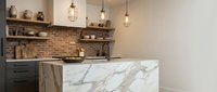 Modern kitchen interior with marble island, exposed brick backsplash, industrial pendant lighting and floating wooden shelves for contemporary home design.