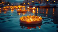 Floating diya oil lamp with marigold petals on water during evening festival celebration with warm bokeh lights reflecting in background.