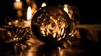 Crystal ball reflecting warm candlelight creates mystical atmosphere for fortune telling, meditation, and spiritual practices in cozy interior setting.