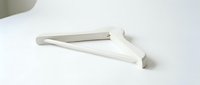 White minimalist clothes hanger lying flat on a clean white surface, soft shadows, modern home organization concept for fashion and retail design.