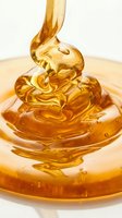 Golden honey pouring onto a swirled heap, creating glossy, translucent waves. Ideal for food, wellness, and culinary design projects.