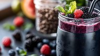 Fresh berry smoothie layered in glass jar with blackberries, raspberries and mint leaves on dark background, healthy breakfast drink with fresh ingredients.