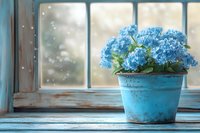 Blue hydrangea flowers in vintage turquoise pot on rustic windowsill with soft natural light and bokeh effect, creating cozy home atmosphere.