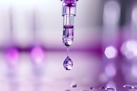 Macro shot of liquid drop falling from glass pipette with purple bokeh background, capturing moment of surface tension in laboratory setting. Scientific research concept.