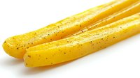 Fresh yellow bell pepper strips seasoned with black pepper and herbs on white background, isolated food ingredient for cooking and healthy eating.
