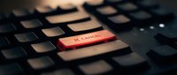 Red cancel button on black computer keyboard with shallow depth of field highlighting the key for web design and user interface concepts.