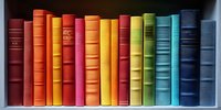 Row of colorful vintage books arranged in rainbow spectrum order on white wooden shelf, spines showing gradient from red through orange, yellow, green to blue.