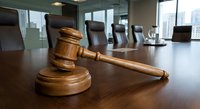 Wooden judge gavel on polished conference table in modern boardroom with city skyline view through windows for legal business meetings.
