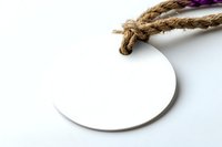 Round white blank tag with natural jute rope on white background, isolated product label mockup for branding and design projects.
