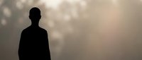 Male silhouette standing in misty atmospheric light with warm golden tones and soft bokeh background for contemplative design projects.