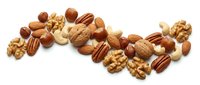 Mixed nuts collection with walnuts almonds pecans hazelnuts on white background isolated for healthy snacking and cooking ingredient designs.