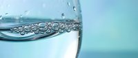 Clear water with bubbles in glass against soft blue background for hydration wellness and refreshment concepts in commercial advertising campaigns.