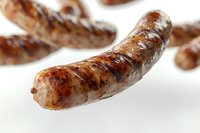 Grilled bratwurst sausage with crispy brown crust and juicy meat on white background, macro food photography showing texture and grill marks.