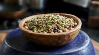 Fresh green mung beans in rustic wooden bowl on blue ceramic plate, healthy legumes for cooking, sprouting and nutrition in kitchen setting.
