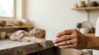 Craftsman hand with turquoise ring displaying woodworking workshop with tools and materials, suitable for artisan, handmade business, and creative professional content.