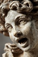Ancient stone sculpture face with dramatic expression and curly hair detail showing classical art craftsmanship and weathered texture for historical design projects.
