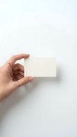 Female hand holding blank white business card mockup against clean white background for branding and corporate identity design projects.