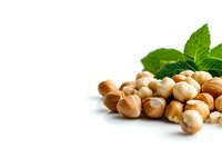 Fresh hazelnuts scattered with green leaves on white background, macro food photography showing natural texture and details. Suitable for healthy eating concepts.