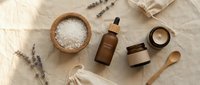 Natural spa essentials with lavender, sea salt, essential oil bottle and wooden accessories arranged on linen fabric for relaxation and wellness rituals.