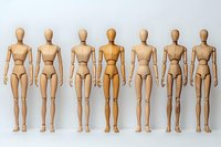Wooden artist mannequins standing in row on white background, one highlighted in different tone, representing uniqueness and individuality concept.