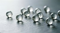 Clear glass marbles scattered on reflective surface creating elegant minimalist composition for modern interior design and decorative projects.