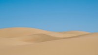Vast desert landscape with rolling sand dunes under clear blue sky, suitable for travel, nature, and background design projects.