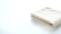 Folded beige linen fabric on white background, isolated textile for design, home decor, and fashion projects.