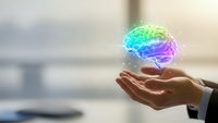 Businessman hands holding glowing colorful brain hologram representing artificial intelligence, innovation and creative thinking in modern office.