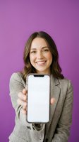 Smiling young Caucasian businesswoman in checkered blazer showing smartphone screen on purple background for mobile app presentation and marketing.